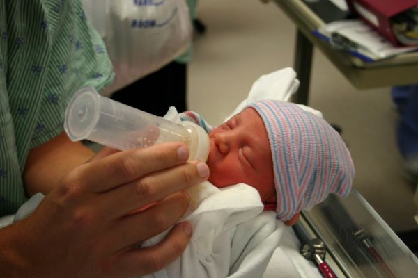 baby drinks breastmilk from bottle
