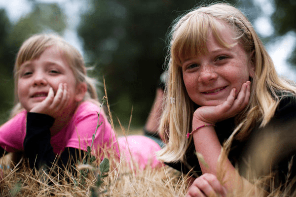Two girls smiling, laying in the grass