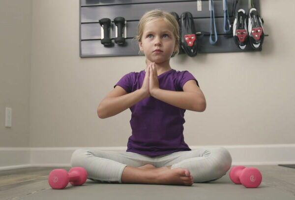 blonde girl sitting cross legged on a mat practicing yoga