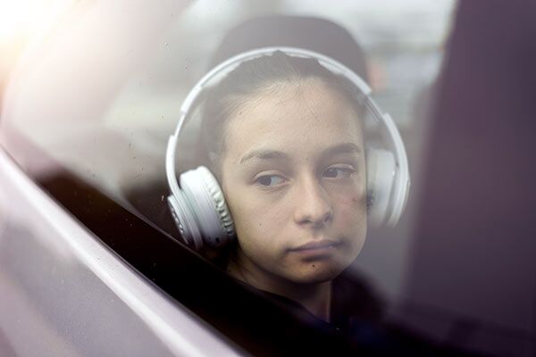 child wearing headphones looking out car window