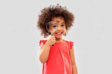 Child holding magnifying glass to eye 