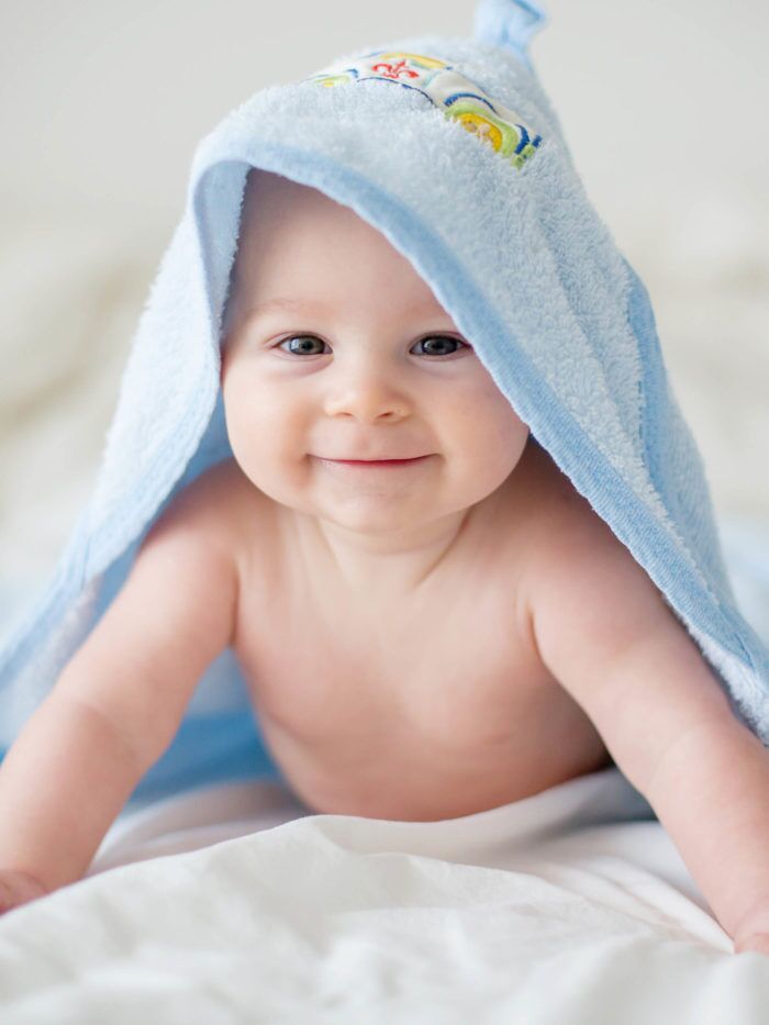 Cute little baby boy, relaxing in bed after a bath