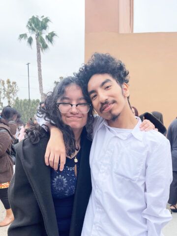 Siblings Hector and Elizabeth smile with their arms around each other