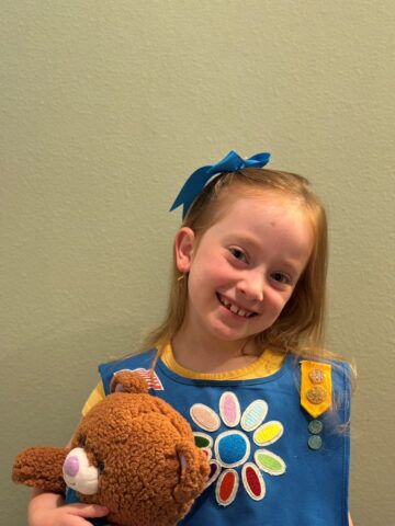 young girl in a flower dress holding a teddy bear