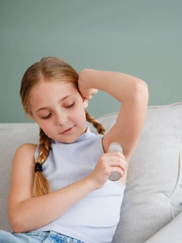 girl applying deodorant - body care tips for girls with autism