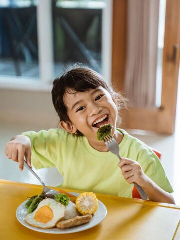 cute little girl having healthy breakfast at home by herself