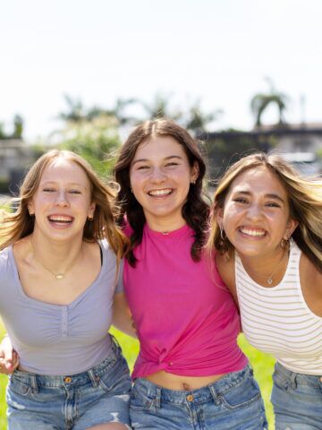 Three teenagers look at the camera and smile together
